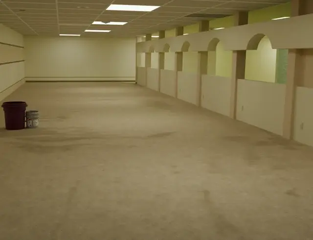 A large room with a carpeted floor and white walls.