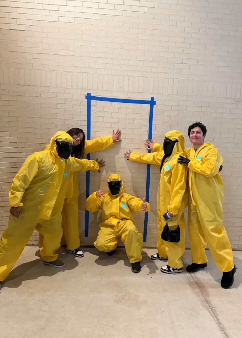 Four people wearing yellow suits and masks pose for a picture.