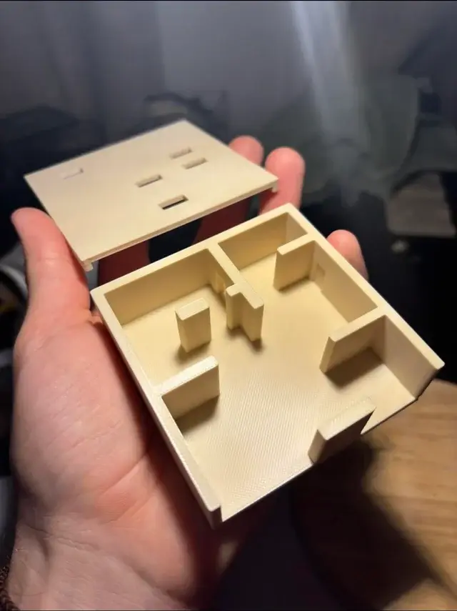 A hand holding a model of a room.