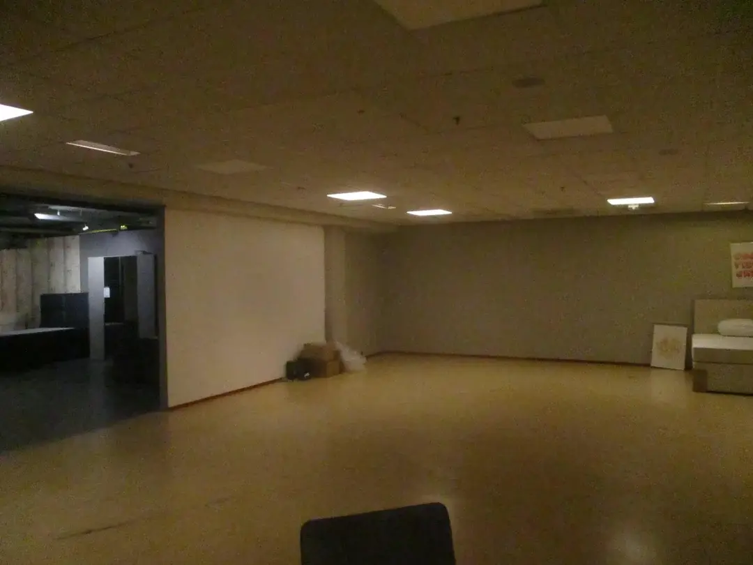A large, empty room with a white wall and a doorway.