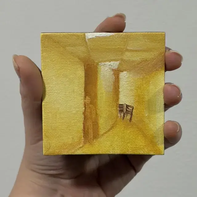 A person holding a painting of a hallway.